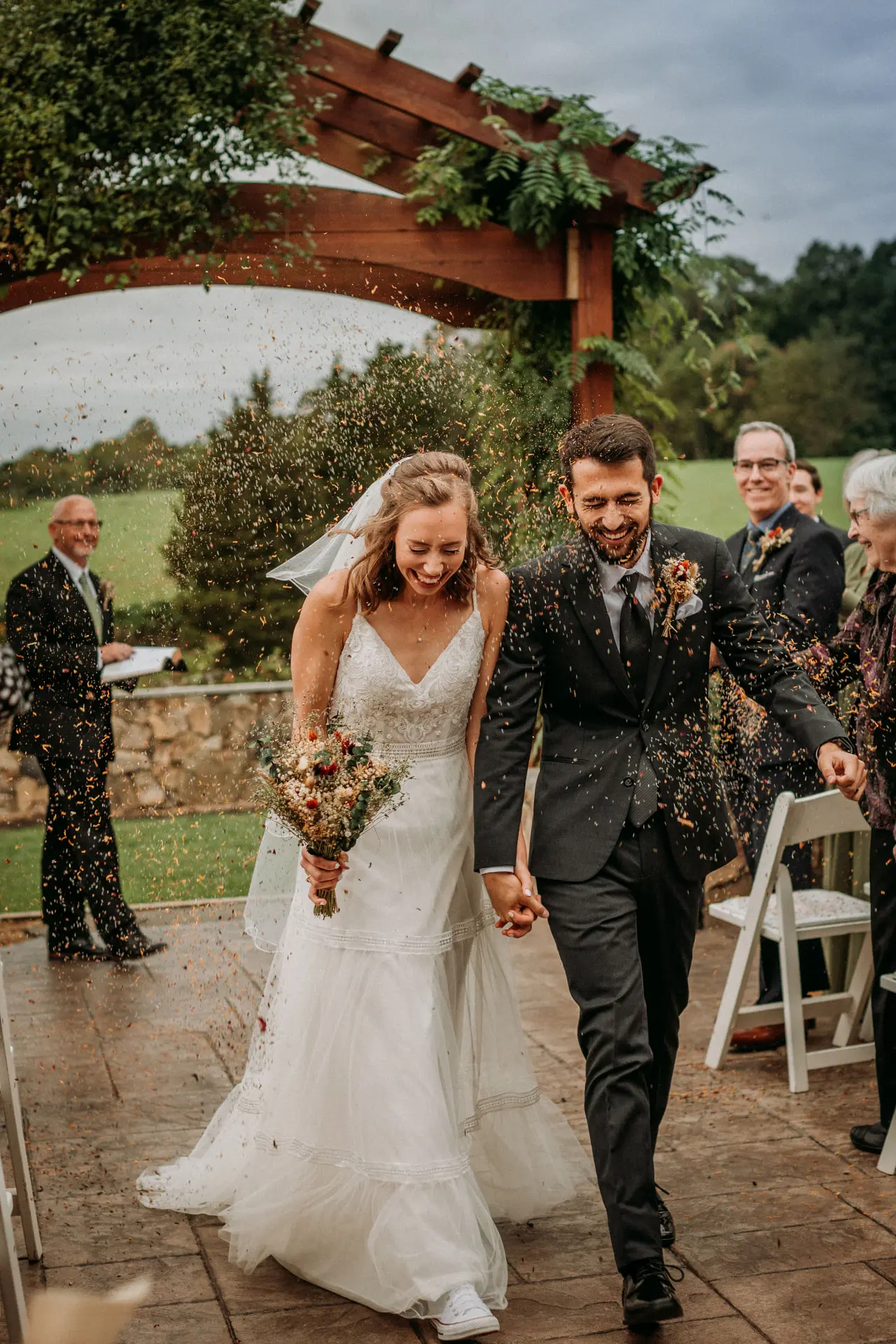 Newlyweds laughing through a confetti recessional