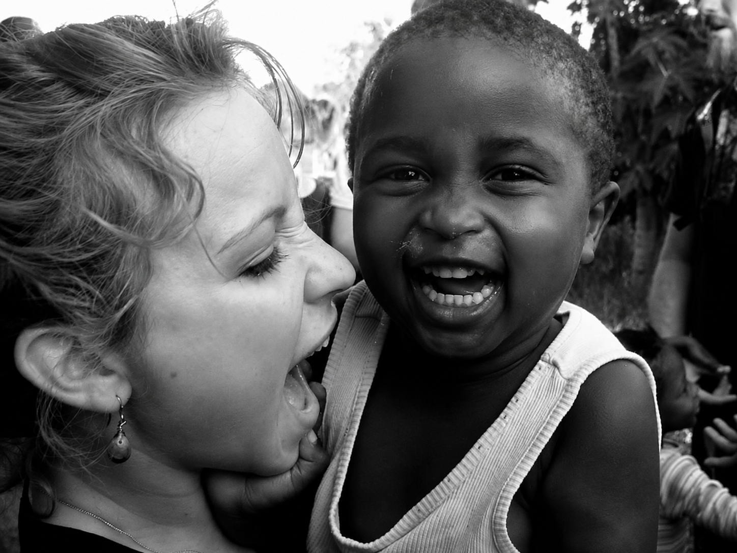 Black and white photograph of Rae with a smiling child in South Africa