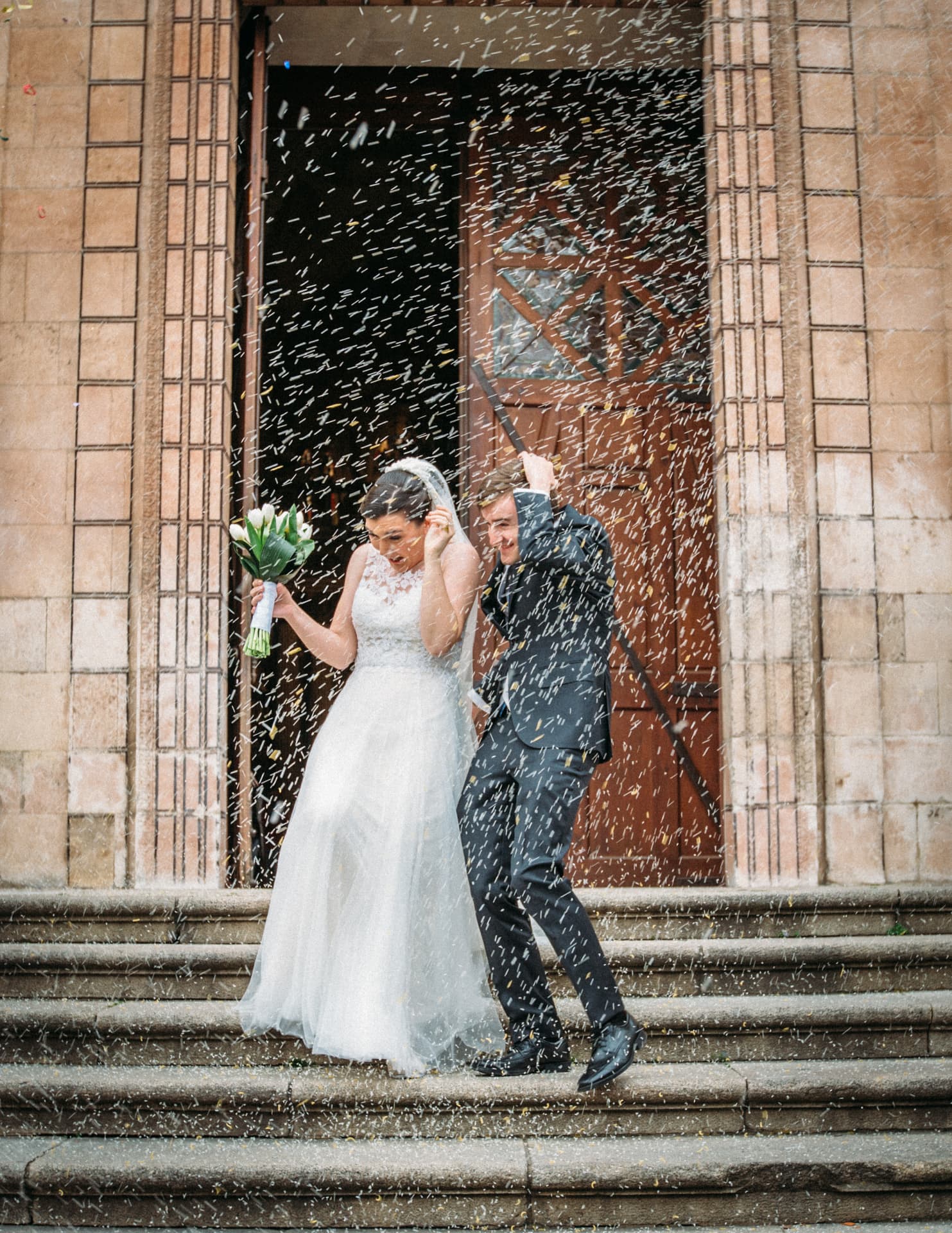 Bride and groom showered with rice on the church steps