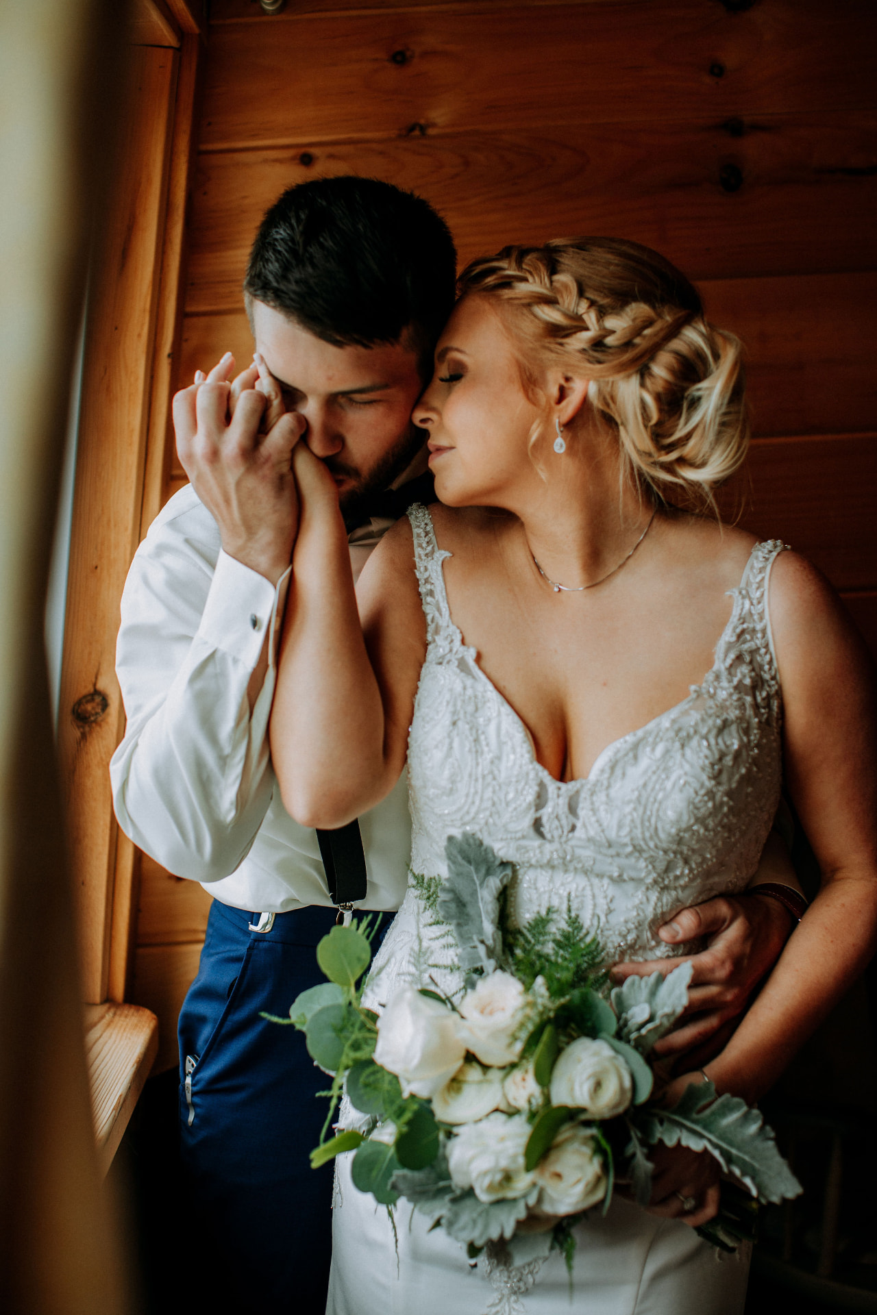 Intimate portrait of a bride and groom embracing in warm wooden light