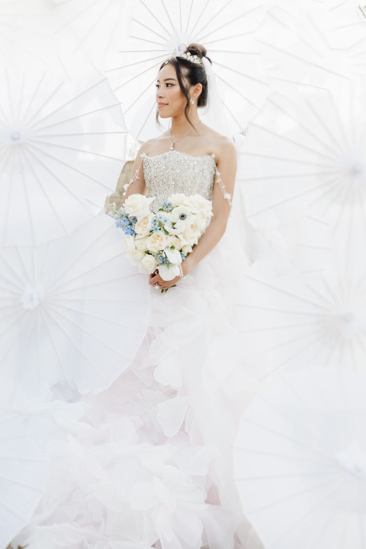 Bride with a parasol holding a white bouquet