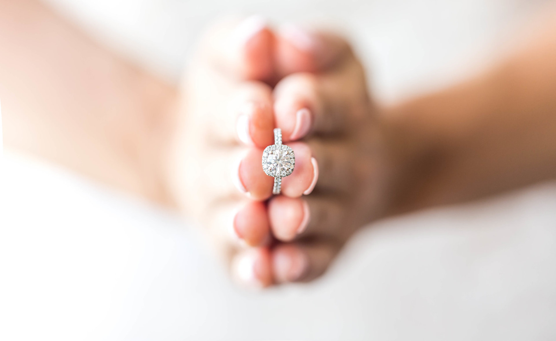 Close-up of an engagement ring held between fingertips