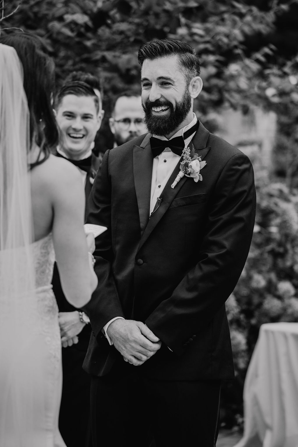 Black and white portrait of a groom smiling during the ceremony vows
