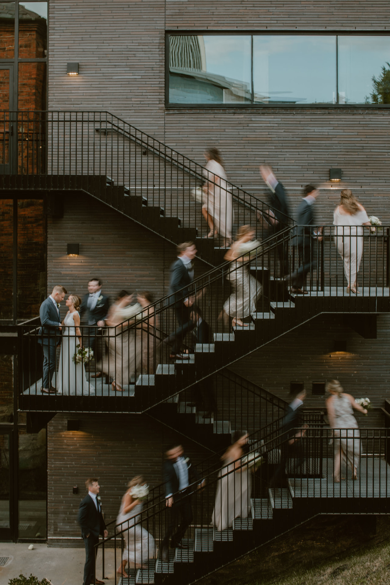 Wedding party moving along an industrial staircase at dusk