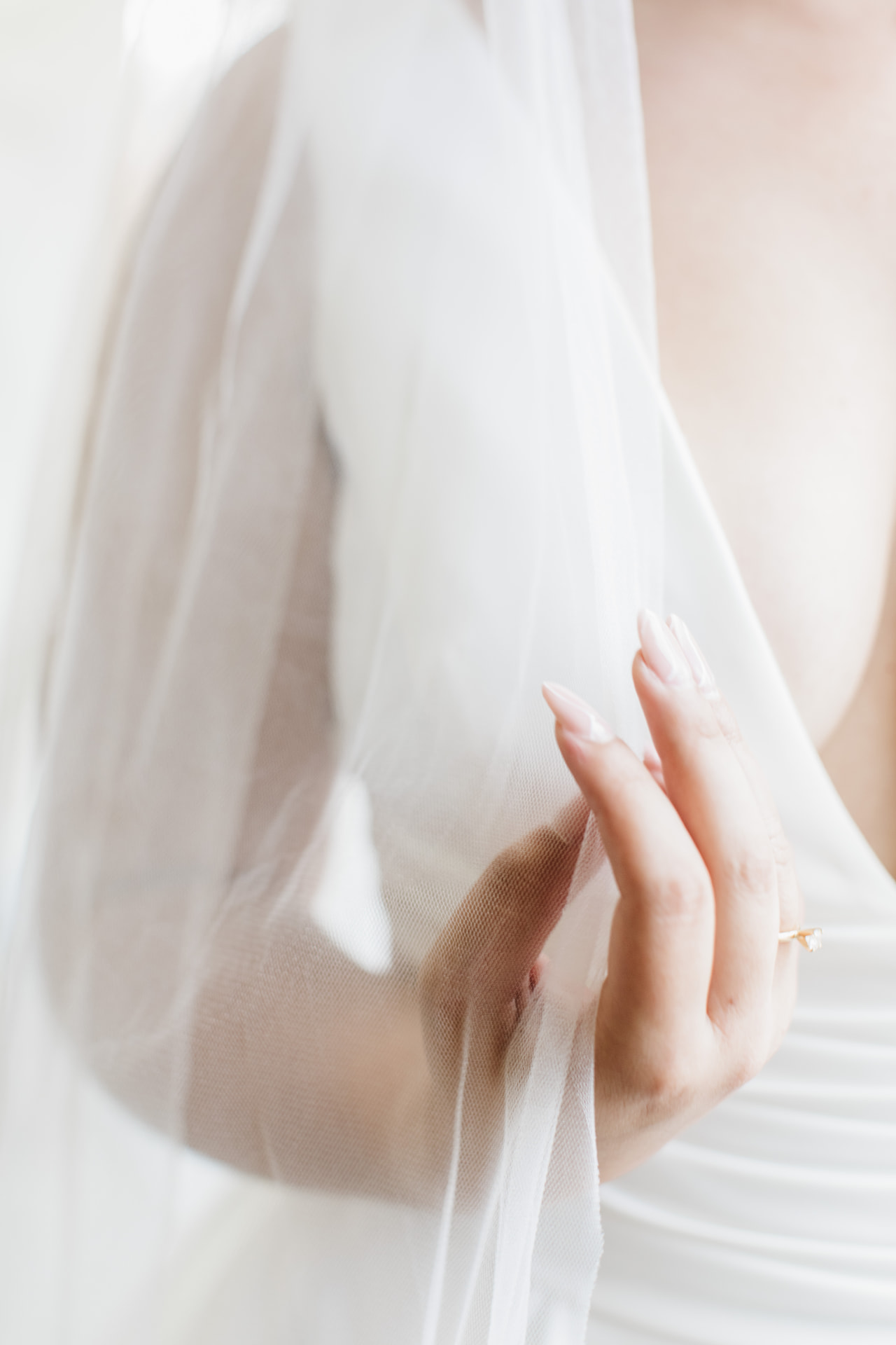 Bride's hand resting against a soft veil