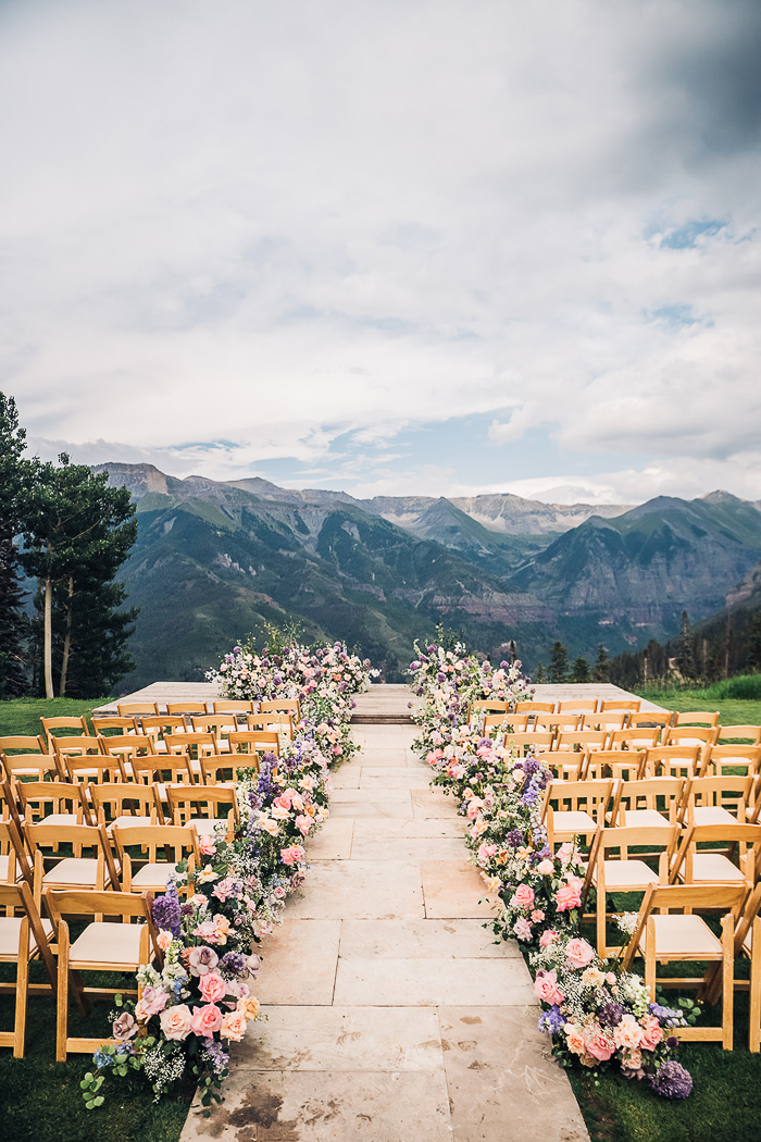 Outdoor mountain ceremony aisle lined with blush and lavender flowers