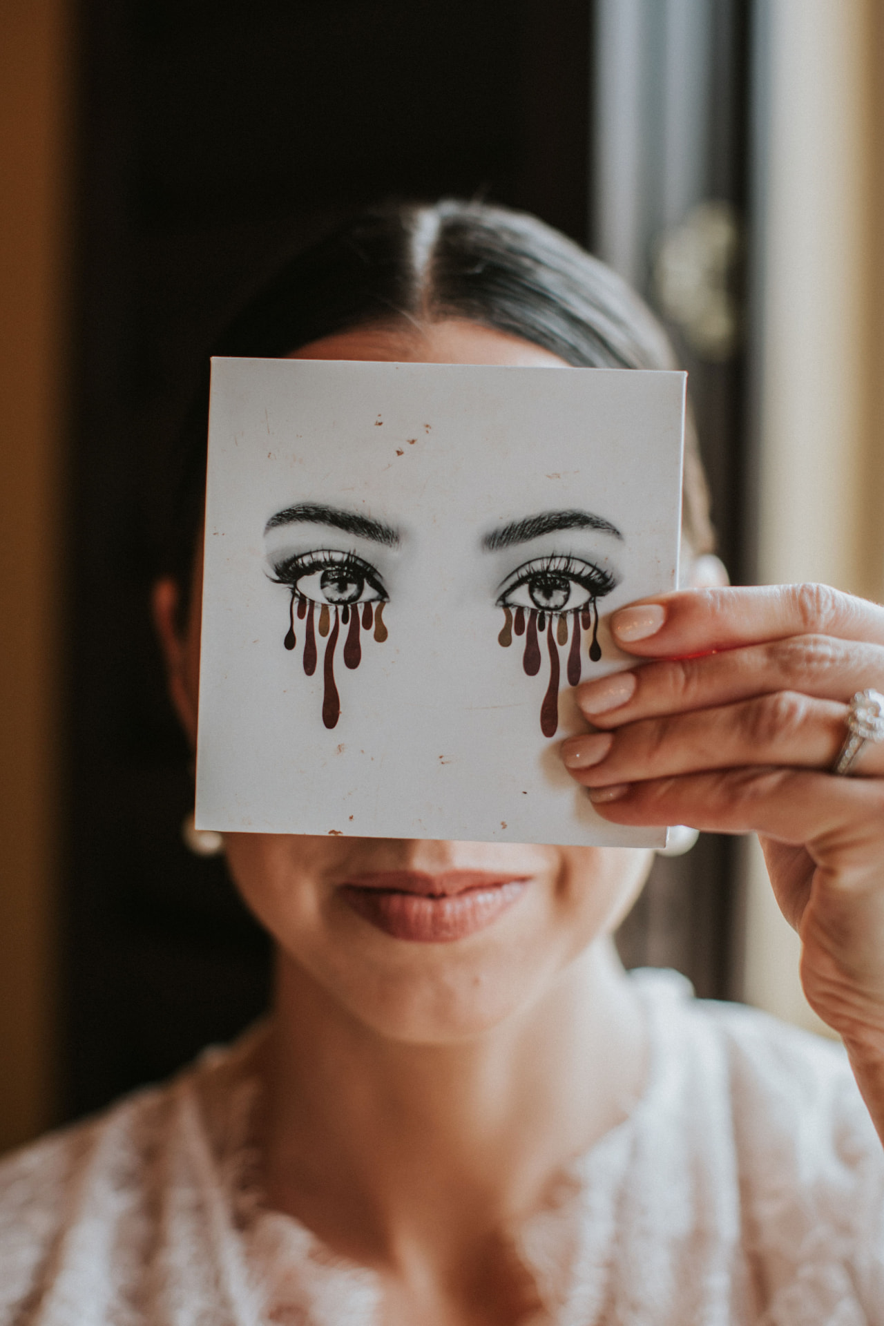 Bride holding an illustrated card in front of her face while getting ready