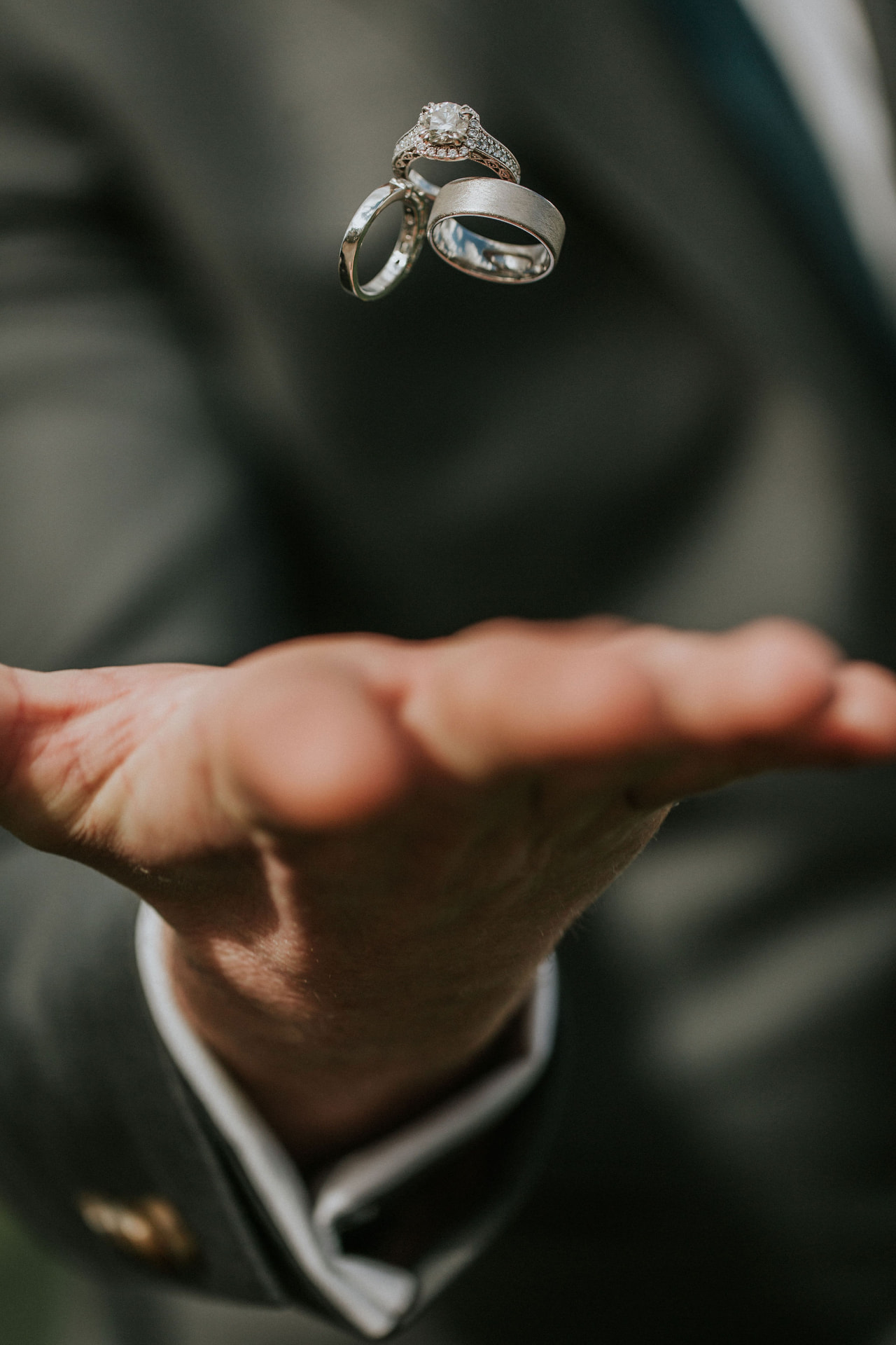 Wedding rings tossed above the groom's open hand