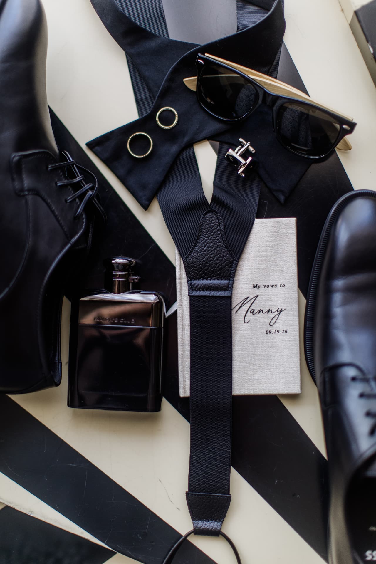 Groom's wedding details arranged with shoes, bow tie, rings, sunglasses and vows