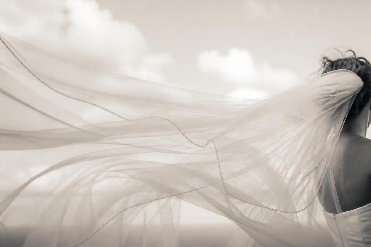 Bride's veil flowing in the wind against a soft sky